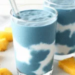 Blue Spirulina Smoothie: Delicious Detox and Superfood Power in One Glass blue spirulina smoothie blue spirulina smoothie in a glass with fruit on white marble background