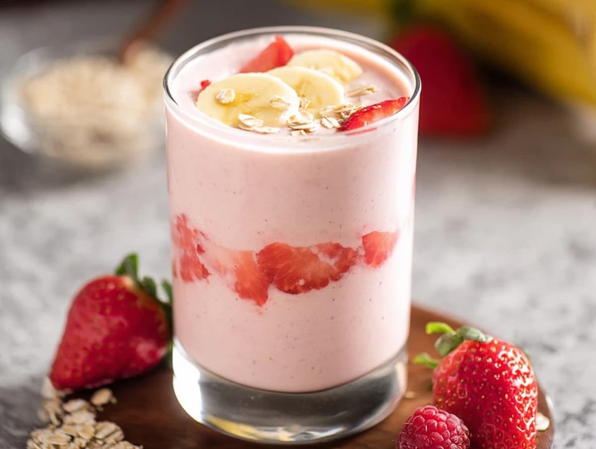 Greek yogurt smoothie in tall glass with fruit and oats