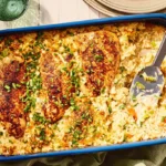 A vibrant chicken and rice casserole in a royal blue baking dish on a rustic wooden table, showcasing delicious chicken casserole recipes.
