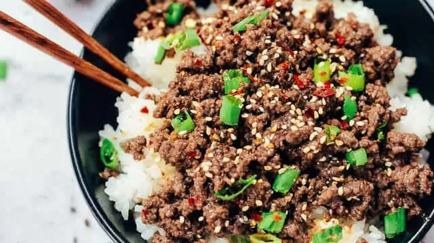 A mouth-watering Korean ground beef bowl with rice, green onions, sesame seeds, and chili flakes.