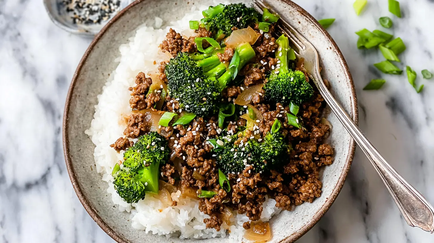 A rustic ceramic bowl filled with a delicious stir-fry of ground beef and broccoli over fluffy white rice, garnished with sesame seeds and scallions on a marble surface.