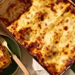 Freshly baked Comforting Million Dollar Lasagna with golden-brown cheese and rich, saucy layers, served on a rustic table.