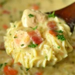 Creamy Crack Chicken Noodle Soup with tender chicken, crispy bacon, and pasta, served on a wooden spoon.